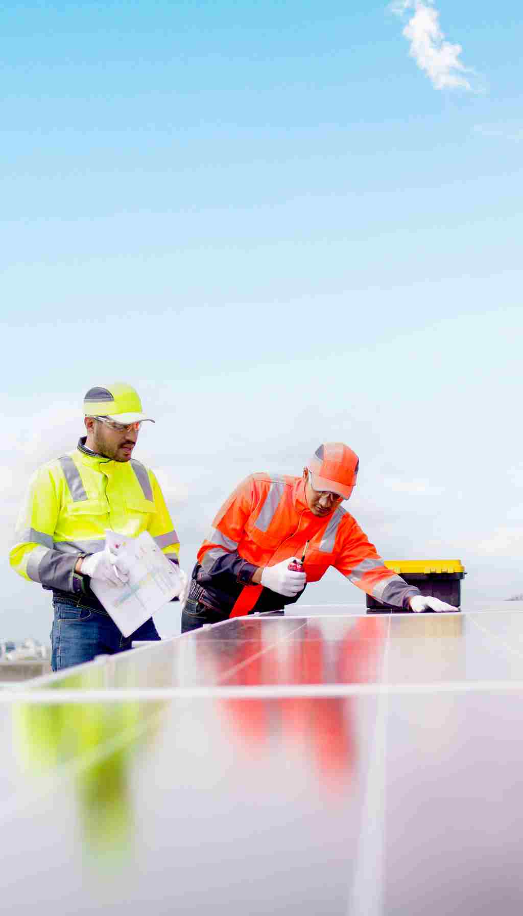 Two engineers in high-visibility jackets inspecting solar panels on a rooftop, reviewing safety plans to ensure compliance with HSA inspection standards in Ireland.