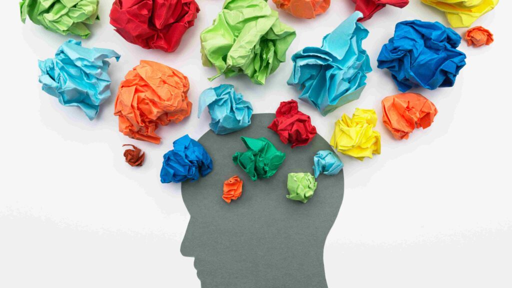 Silhouette of a head filled with colorful crumpled paper representing stress and mental health awareness in the workplace