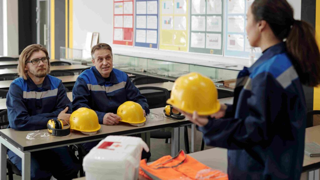 A team of employees wearing safety gear and discussing workplace safety procedures, symbolising leadership and employee engagement in building a positive safety culture in Irish organisations.