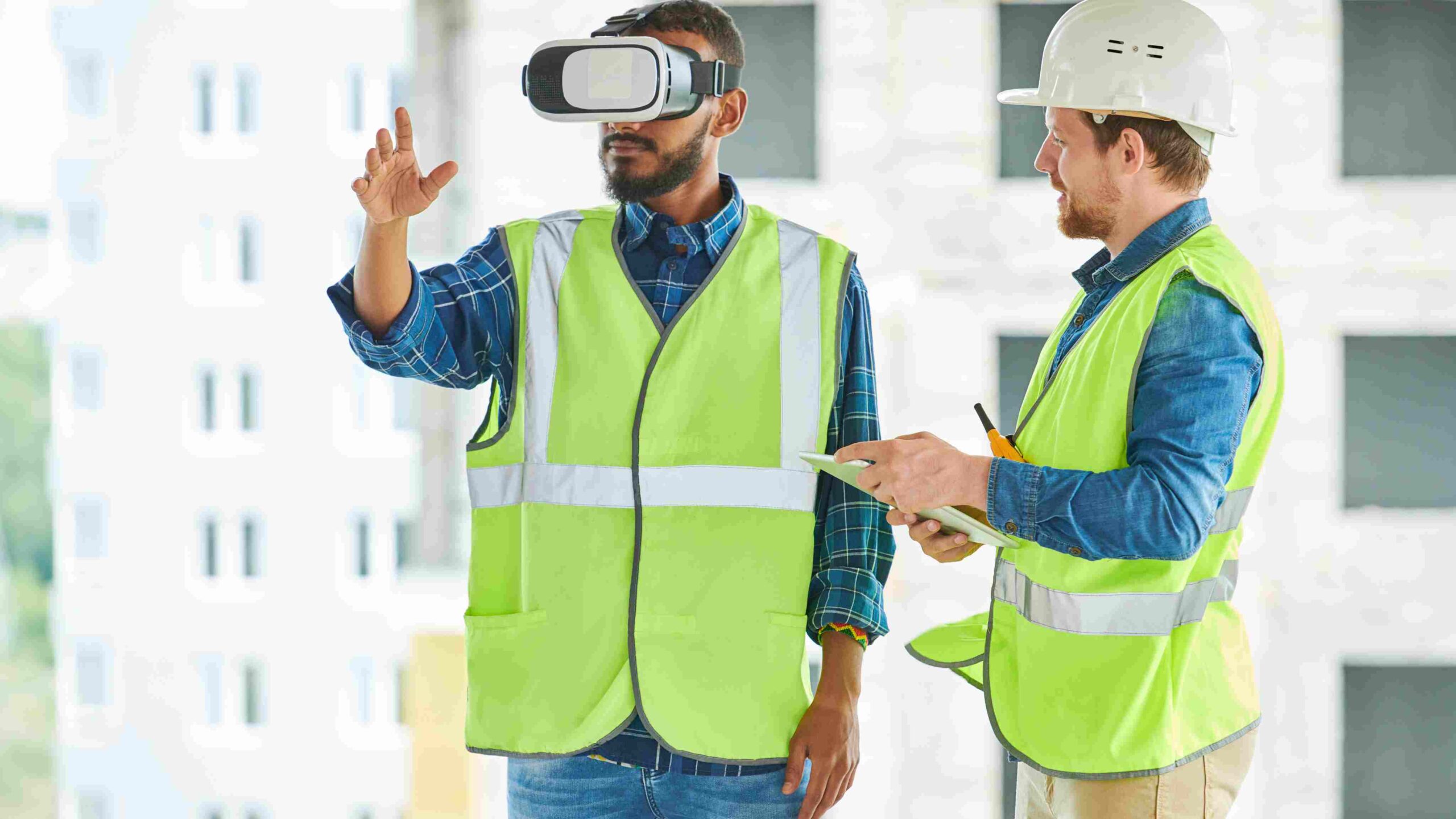 VR Safety Training on Construction Sites Construction worker using a VR headset for safety training while another worker observes and takes notes.