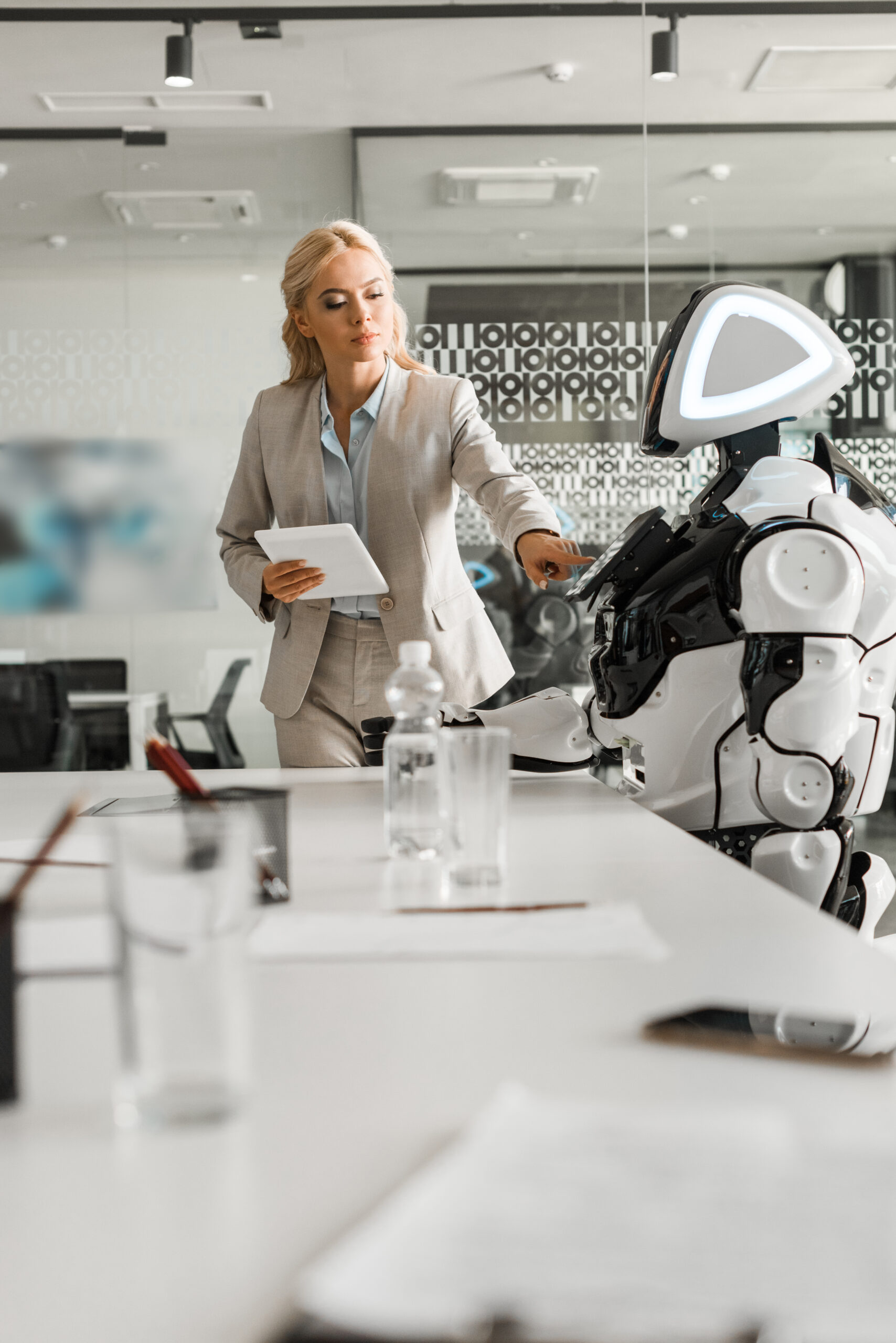 Human–Robot Collaboration in Modern Workplace Safety Businesswoman interacting with an advanced humanoid robot during a meeting, illustrating human–robot collaboration in workplace safety.