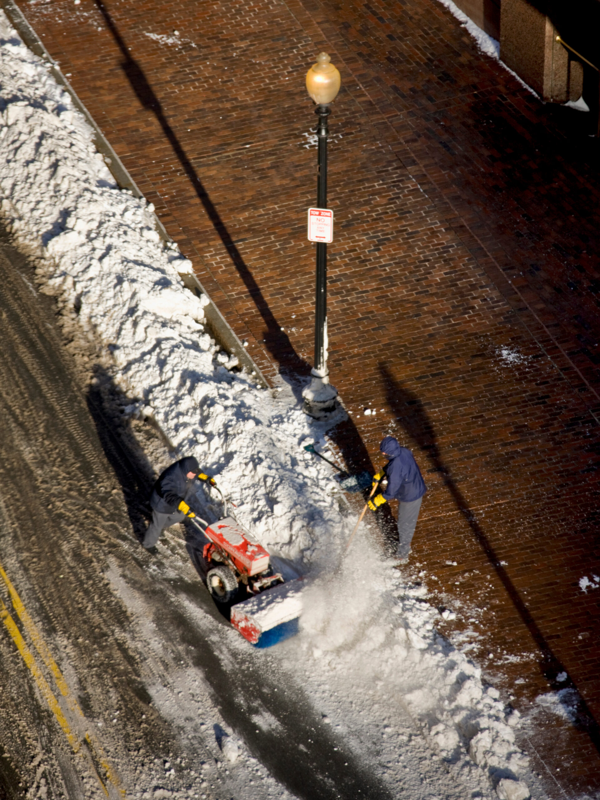 Winter Emergency Response and Snow Rescue Operations Two rescue workers in red jackets digging in deep snow during a winter emergency operation in a forest.