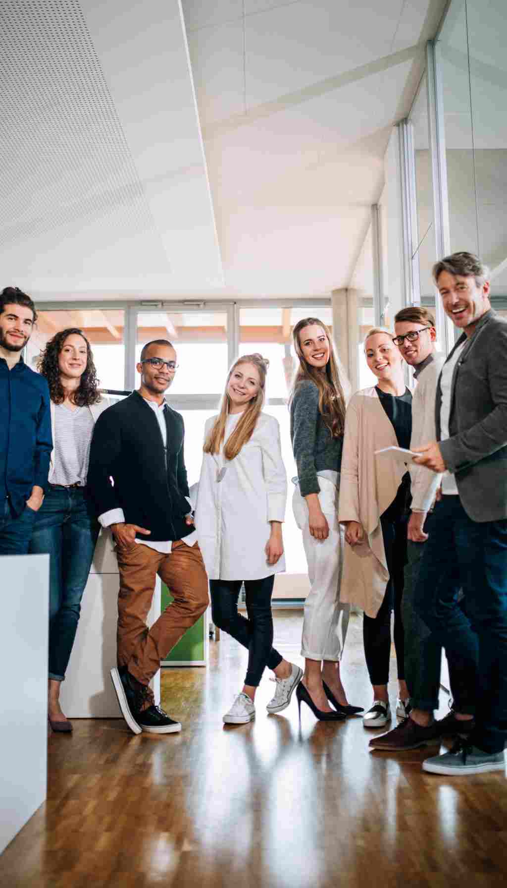 Positive Safety Culture Through Team Collaboration in the Workplace Group of colleagues standing together in a bright modern office, representing teamwork, employee engagement, and a positive safety culture in the workplace.