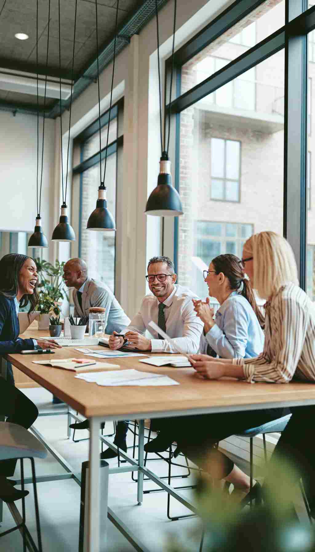 Collaborative Workplace Meeting – Engaging Teams in Safety and Compliance Team of colleagues sitting around a table in a modern office, engaged in a collaborative meeting