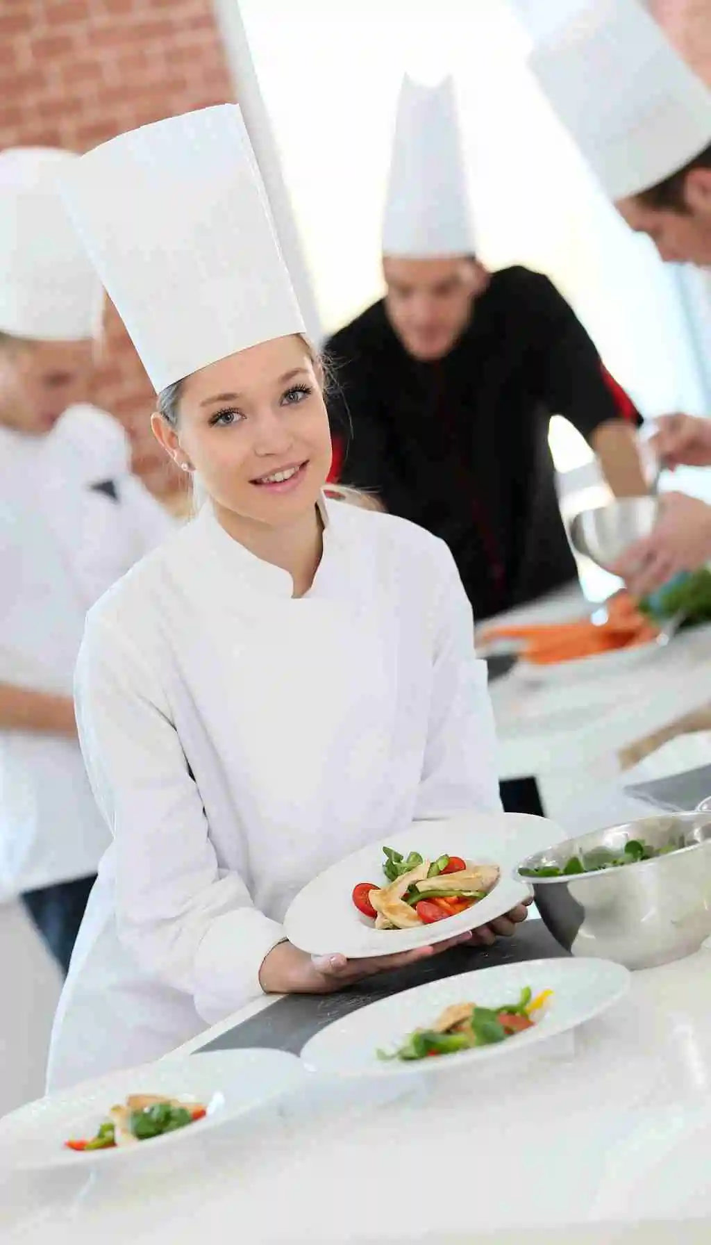 Hospitality trainee plating a dish in a professional kitchen during practical food safety and HACCP training