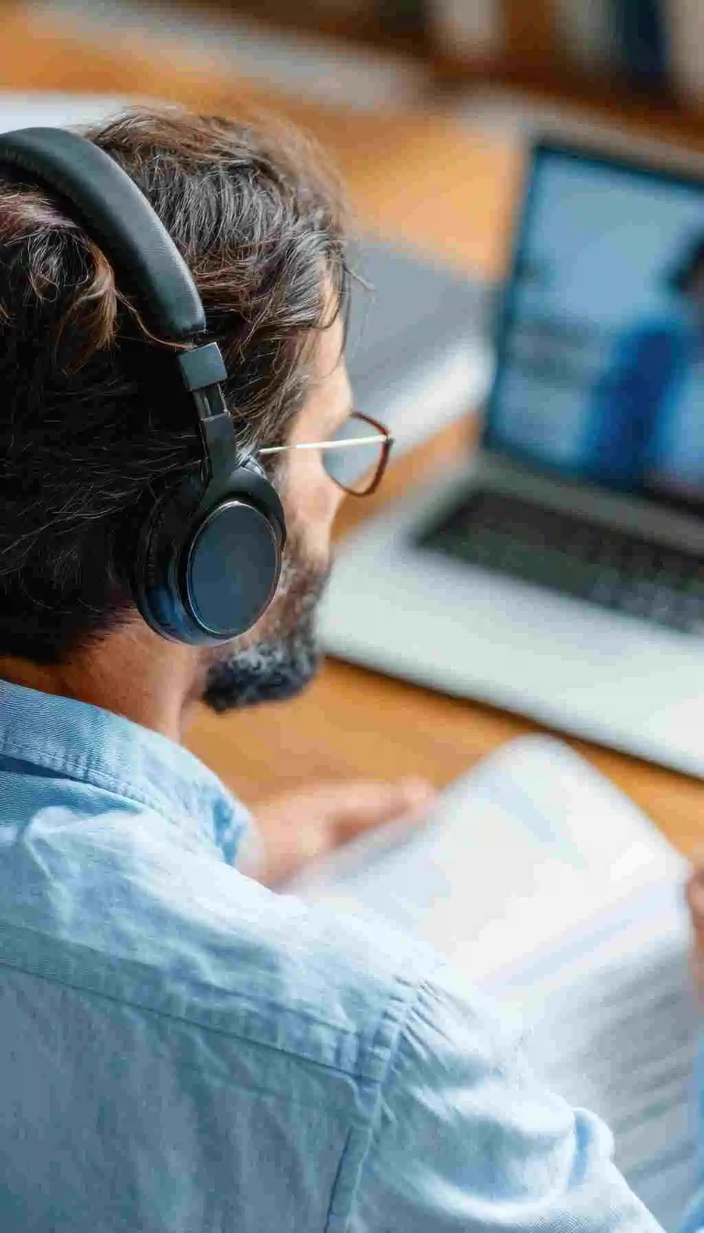 Non-native English speaker completing text-heavy online training on a laptop with headphones, highlighting language barriers in traditional food safety courses.