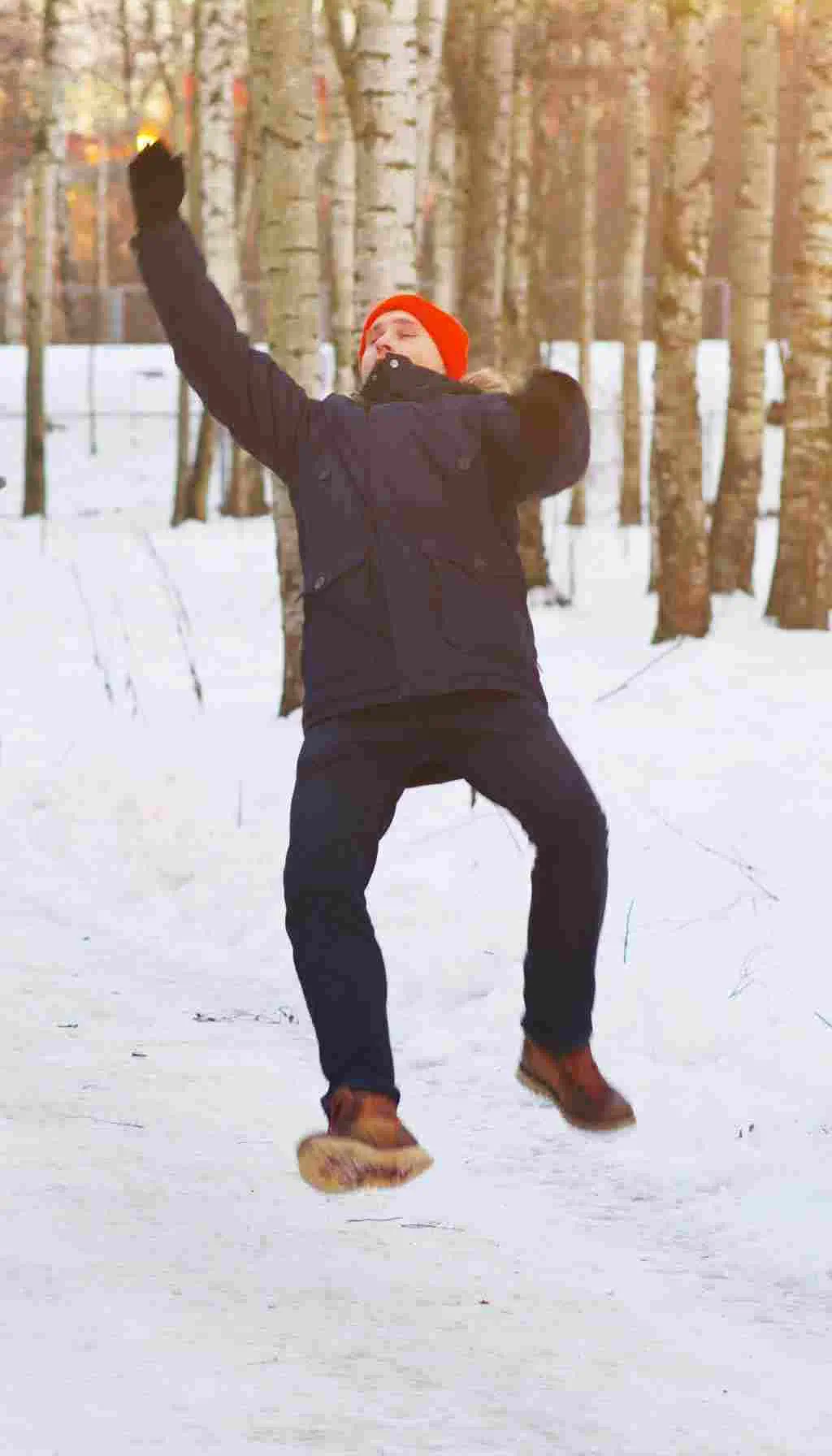 Man wearing winter clothes slipping and falling on icy pavement during snowy weather, showing risk of winter-related injuries