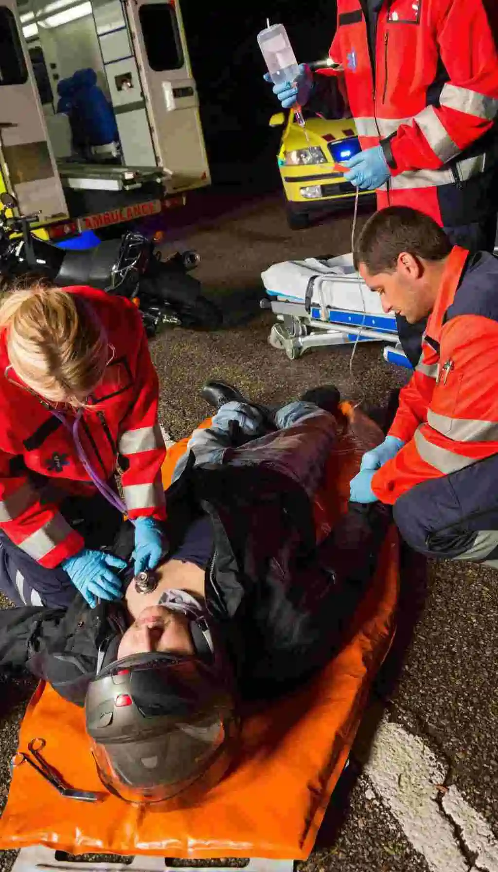 Paramedics providing emergency care to an injured patient beside an ambulance at night