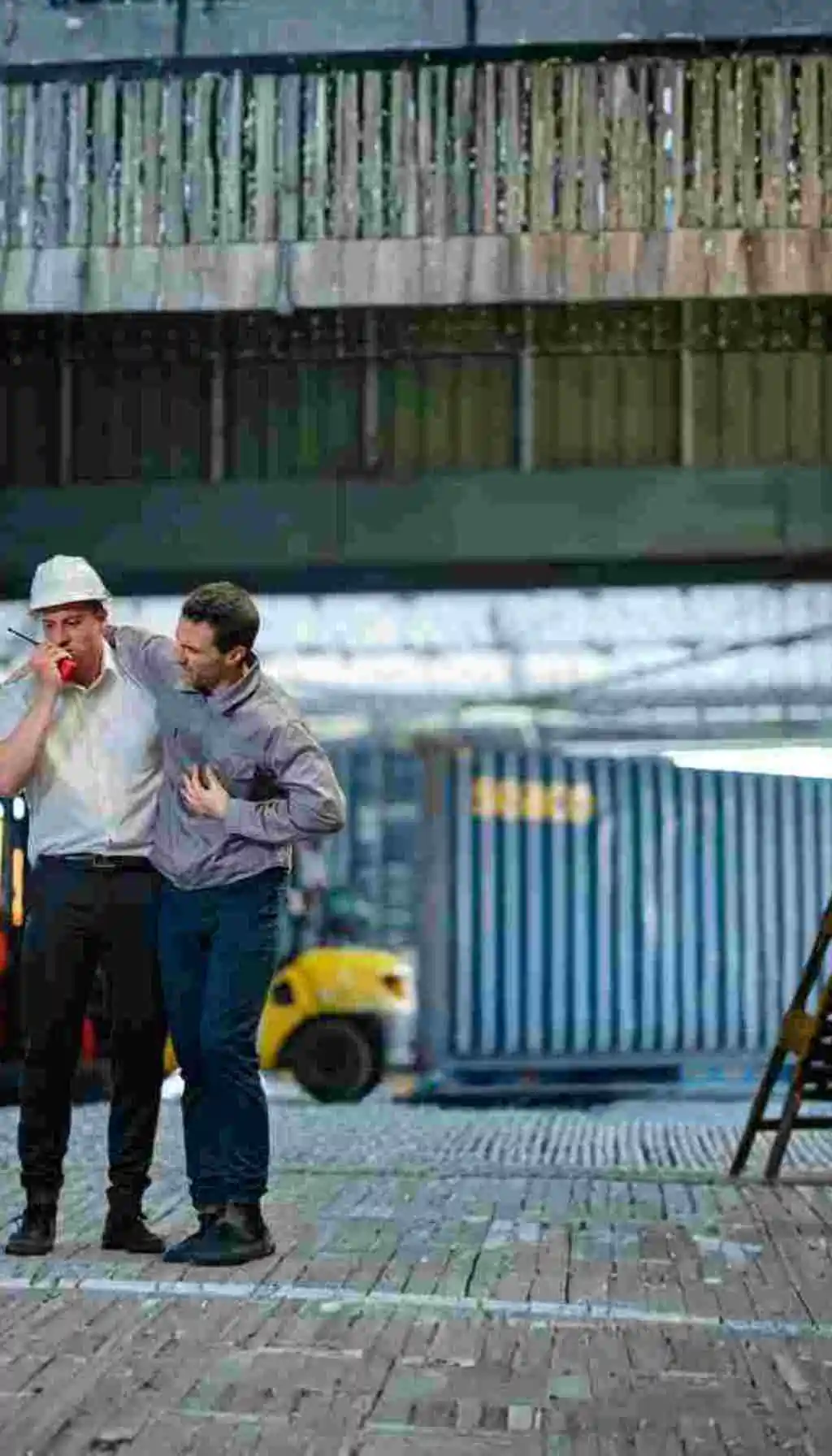 Responding to Health Emergencies: Leadership in Workplace Safety A worker assists a colleague experiencing chest pain in an industrial warehouse, highlighting the importance of quick response and men’s health awareness in workplace safety.