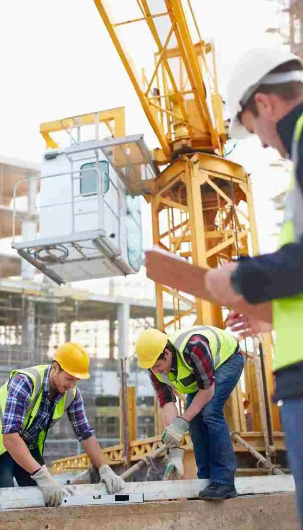 Teamwork and Safety: Building a Health-Conscious Construction Culture Construction workers wearing safety helmets and vests working together on-site under a crane, representing teamwork, safety awareness, and men’s health in the workplace.