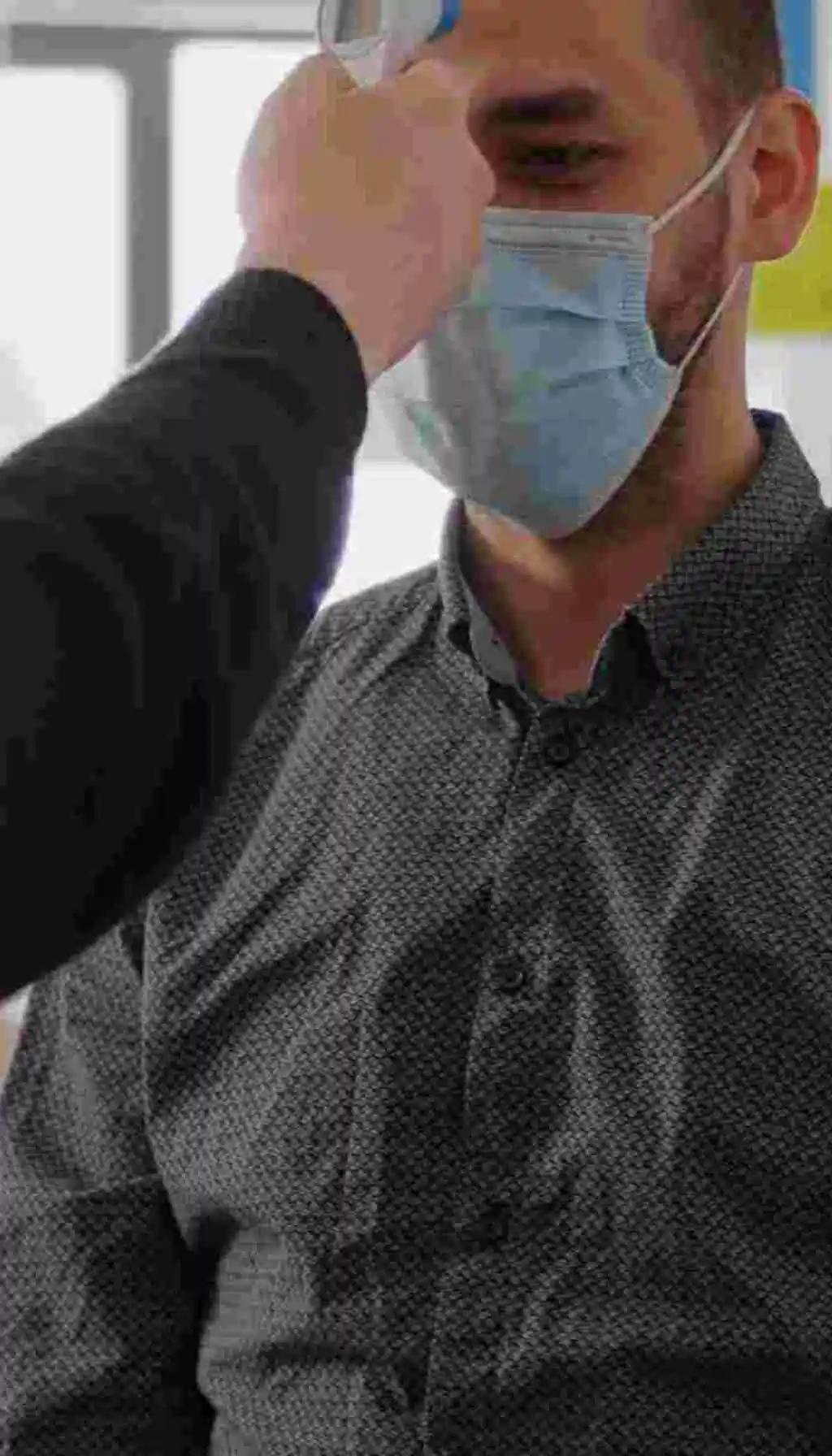 Workplace Health Monitoring: Preventing Illness Before It Becomes a Safety Risk Employee wearing a medical mask having temperature checked with a digital thermometer in the workplace, illustrating proactive health screening and safety protocols.
