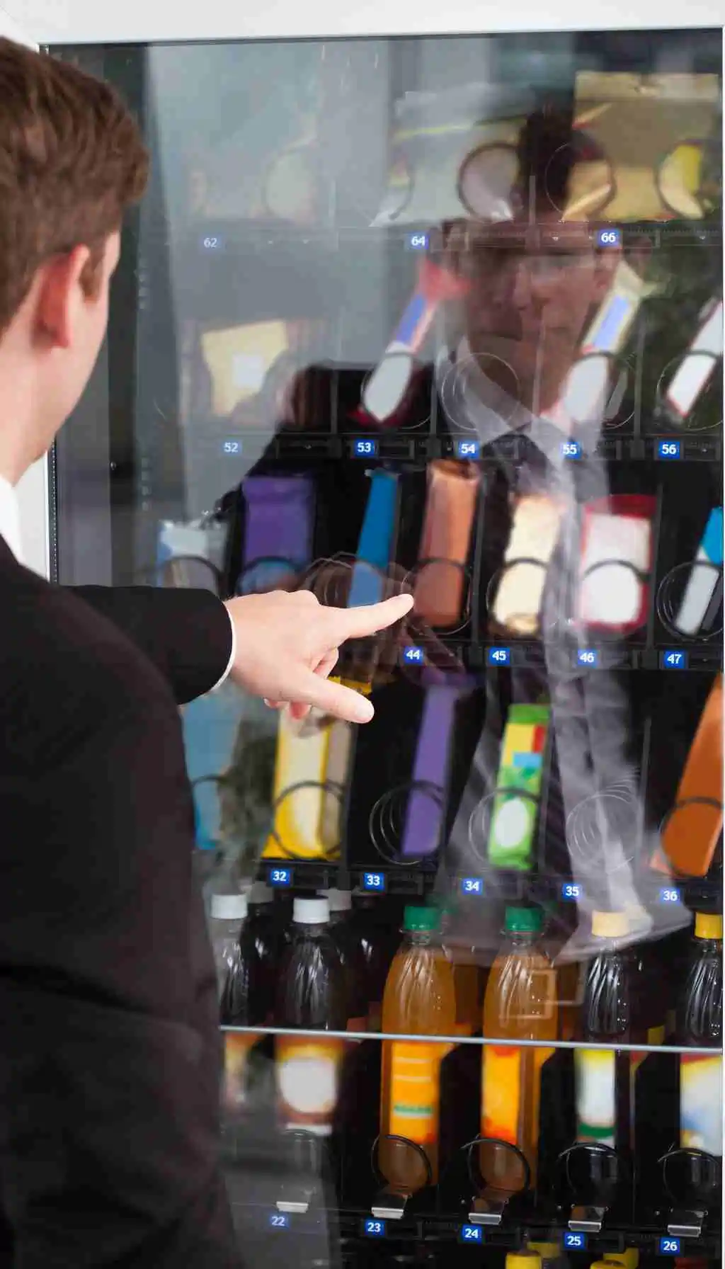 Employee Selecting Snack from Workplace Vending Machine – Allergen Risk Employee pointing at a vending machine snack selection in a workplace, illustrating allergen cross-contact risks from adjacent vending machine coils.