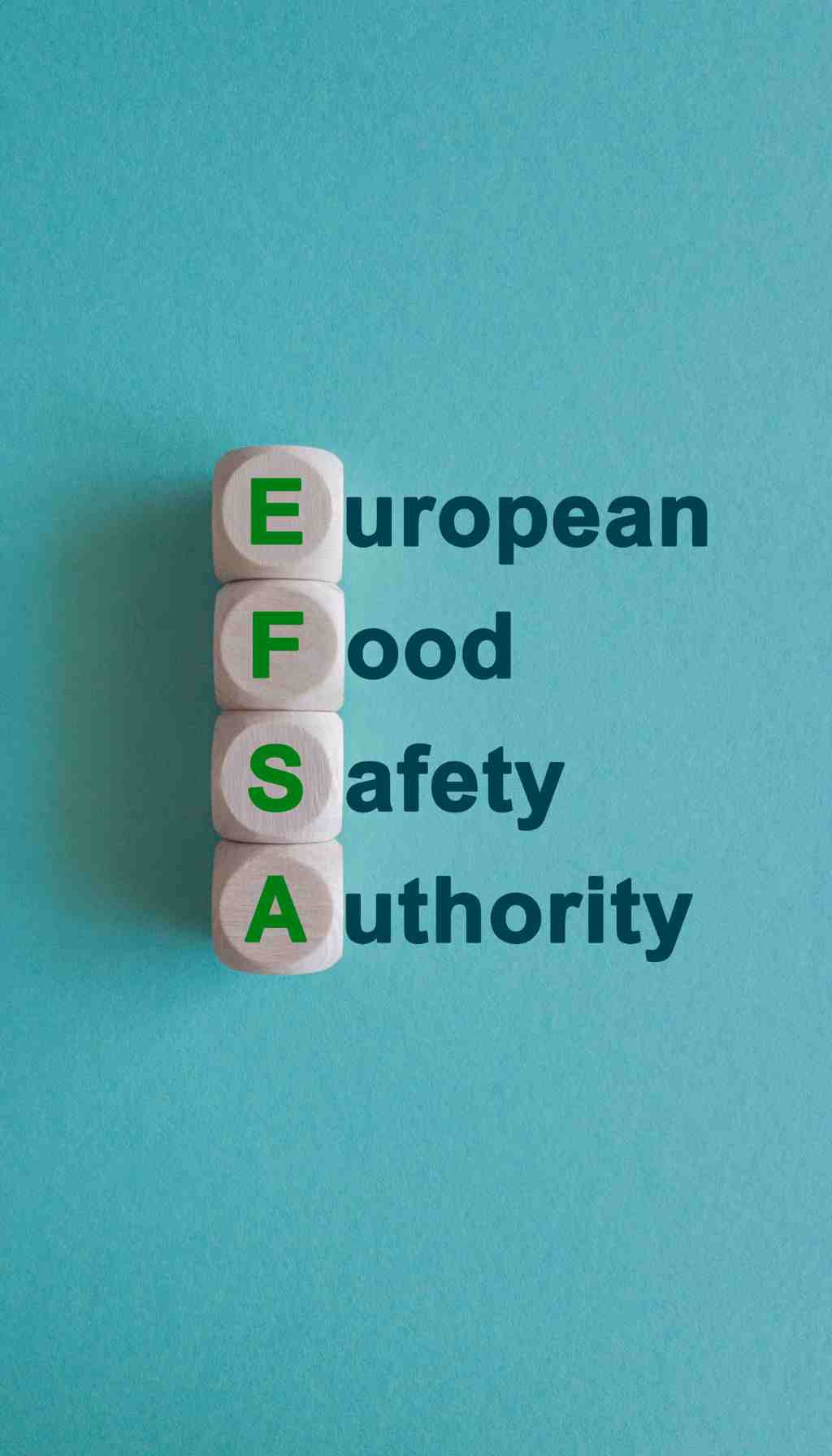 EFSA – European Food Safety Authority Acronym Concept Wooden blocks displaying the letters E F S A stacked vertically beside the words European Food Safety Authority on a blue background.