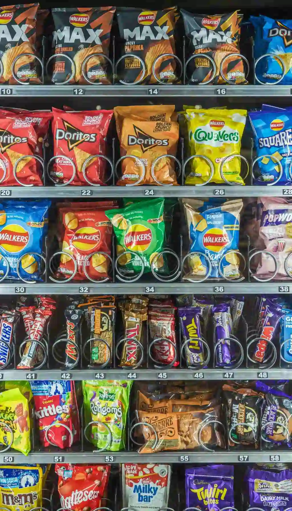 Mixed Allergen Products in Workplace Vending Machine Coils Vending machine shelves with crisps, chocolate bars, and nut-containing snacks stored in adjacent coils, highlighting allergen cross-contact risks.