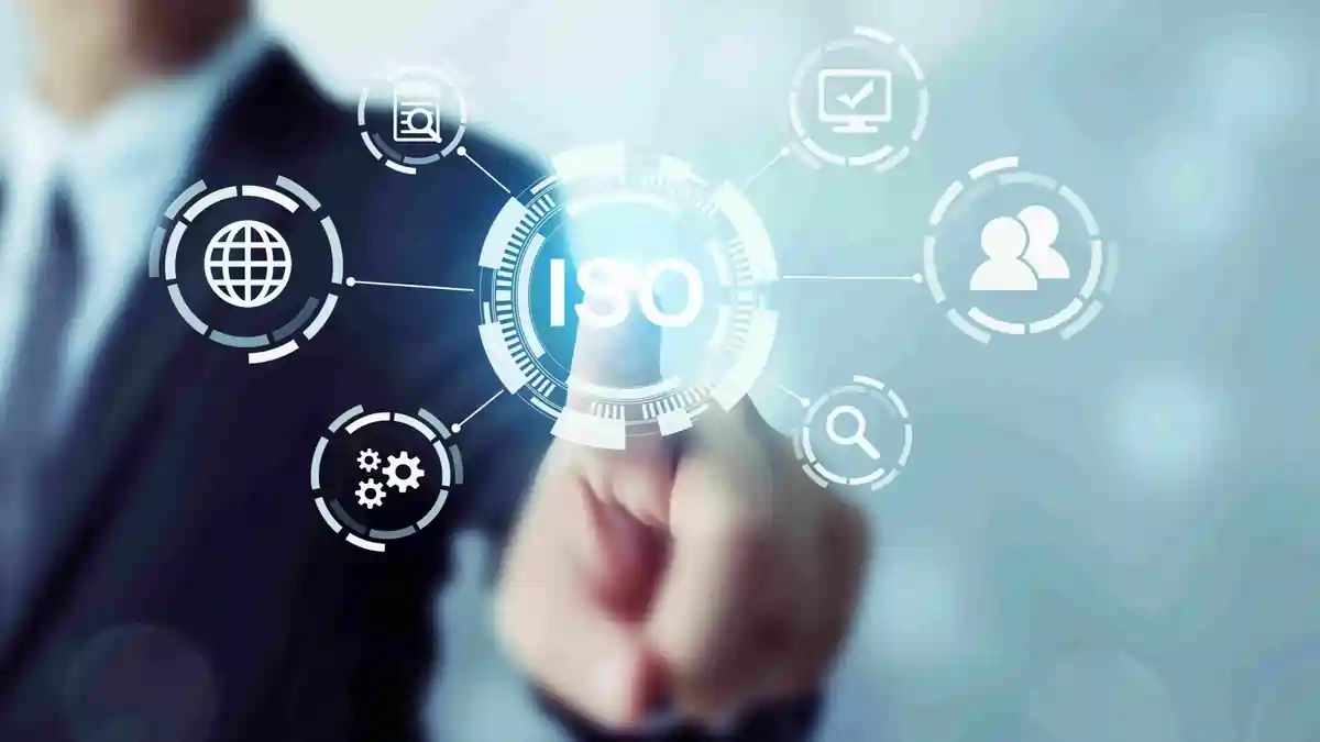 ISO Standards Digital Interface and Compliance Network Business professional touching a digital interface with the ISO logo at the center, surrounded by icons representing global standards, quality, processes, and collaboration.