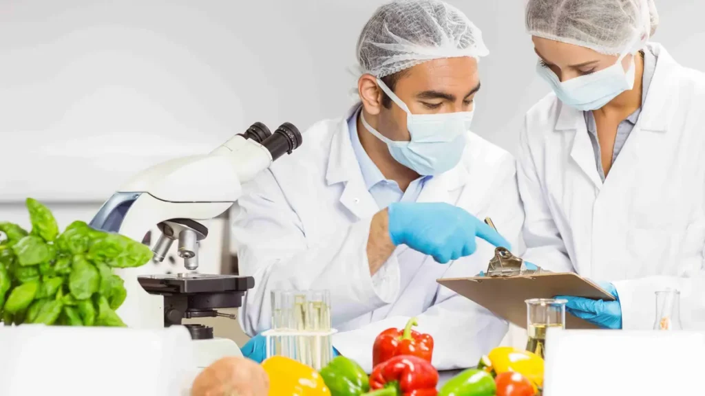 Scientist using microscope to test vegetables in food safety laboratory